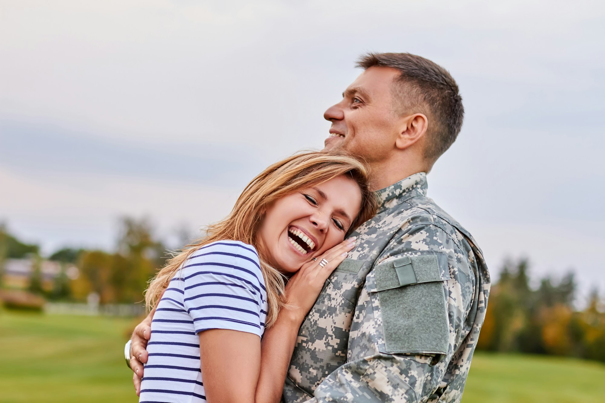 Married soldier hugging wife outdoor.